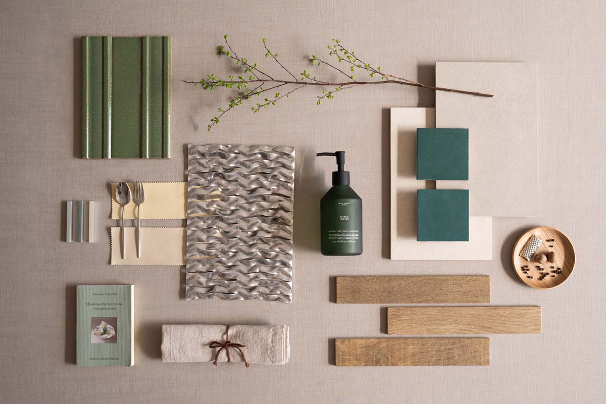 Composizione di materiali e accessori decorativi su un piano chiaro, con piastrelle verdi e elementi in legno effetto naturale.