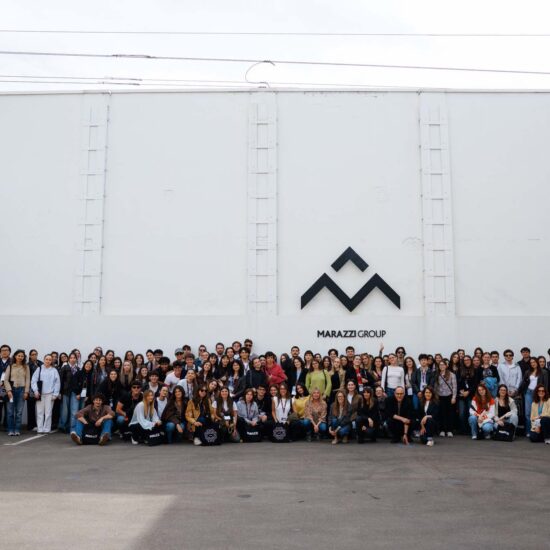 Un grupo de aproximadamente 150 personas posando frente a la pared blanca con el logo "Marazzi Group" en destaque.